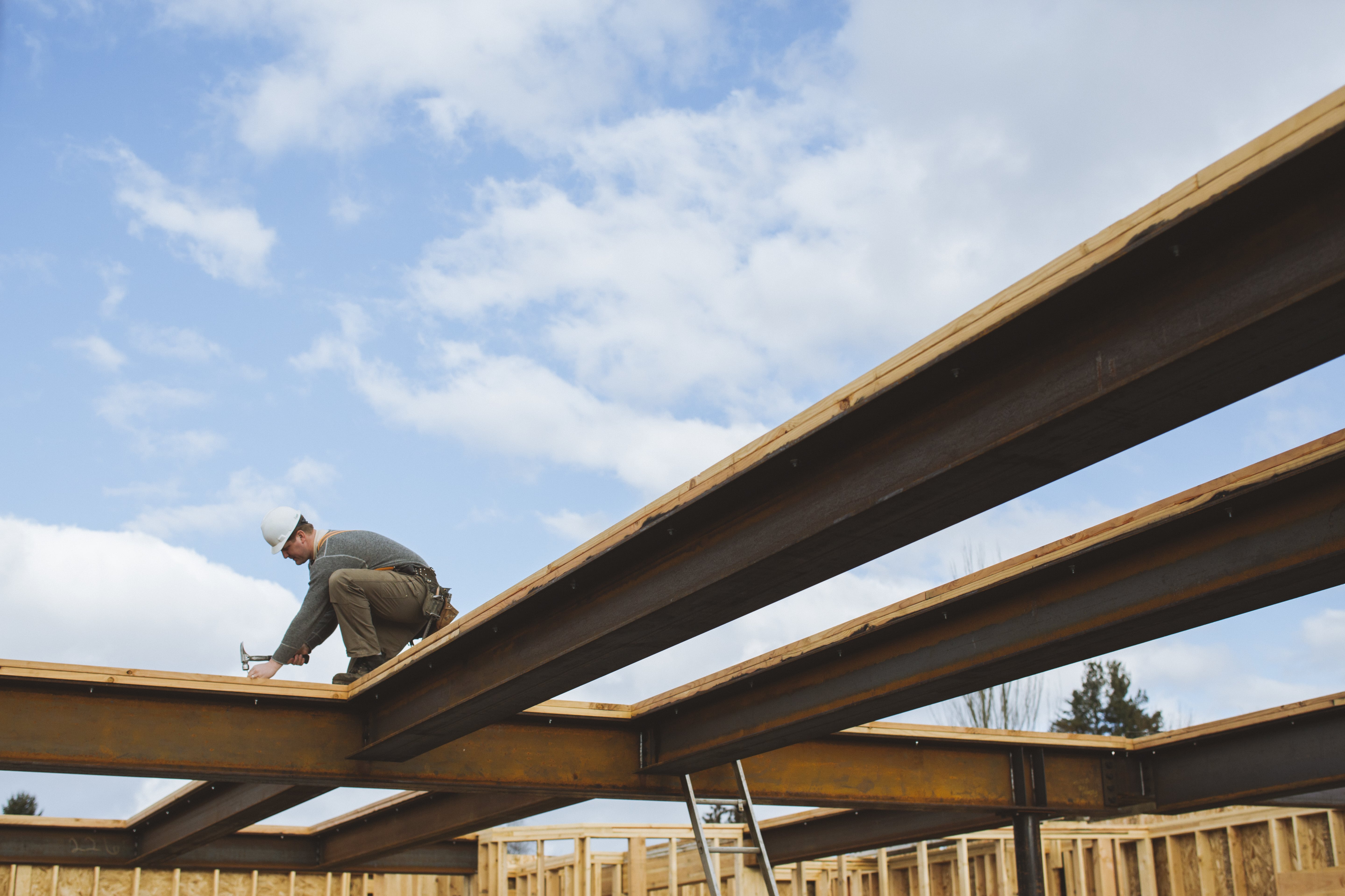Ouvrier travaillant sur une poutre de construction pour poser une charpente.