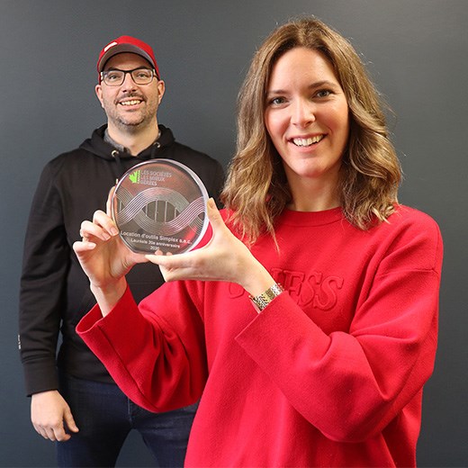 Célestine Véronneau tenant le trophée des Sociétés les mieux gérées, avec Euclide Véronneau en arrière-plan.